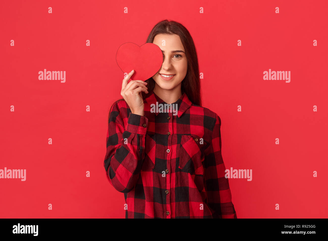 Young girl wearing shirt studio standing isolated on red wall covering ...