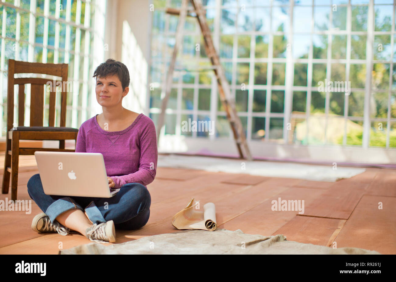 Mid adult woman sitting on the floor with a laptop computer Stock Photo ...