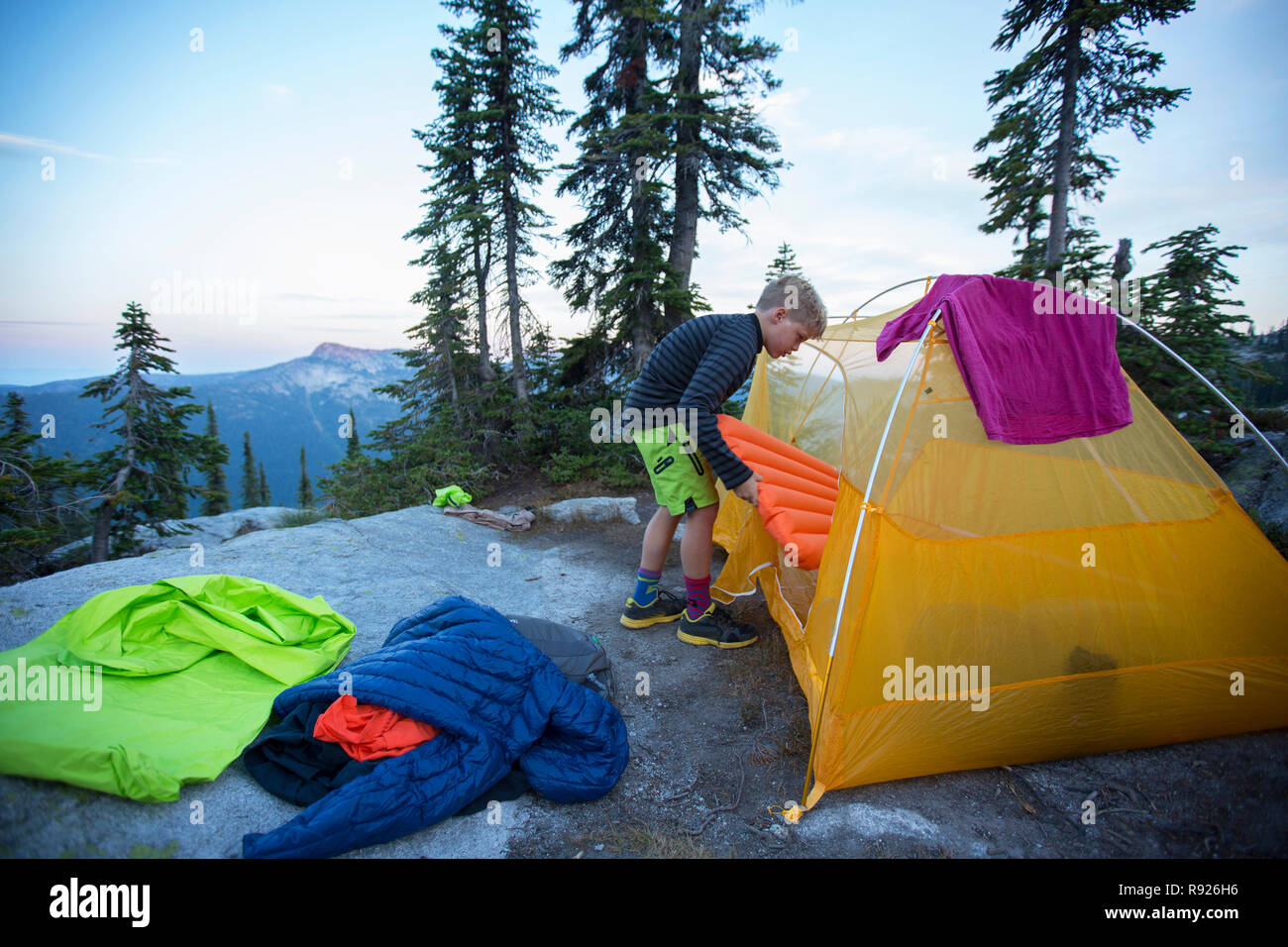 Photograph of a 10 year old boy near a tent preparing for camping, Selkirk Mountains, Sandpoint, Idaho, USA Stock Photo