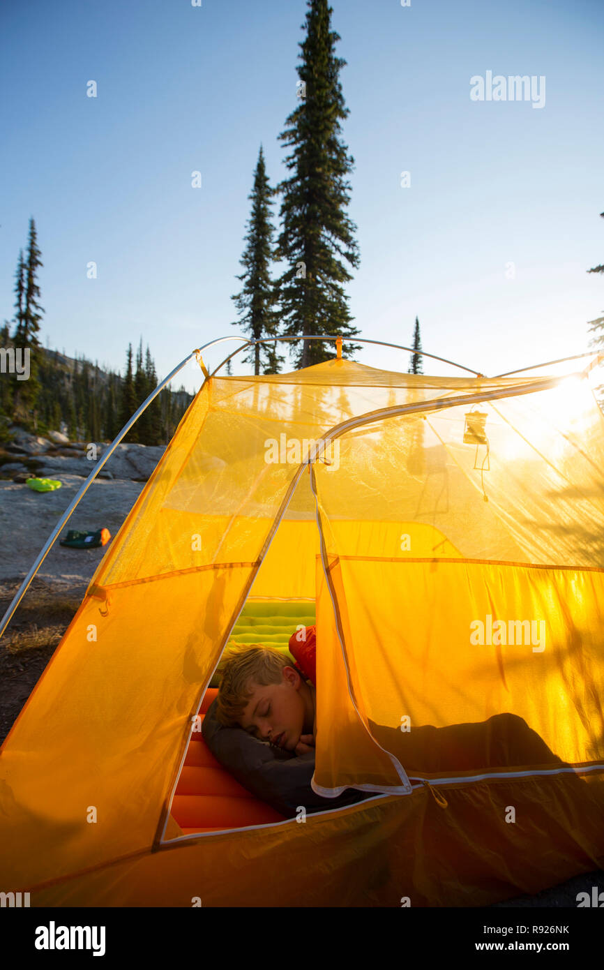 View of a boy sleeping in a tent while on a hiking trip in mountains, Selkirk Mountains, Sandpoint, Idaho, USA Stock Photo