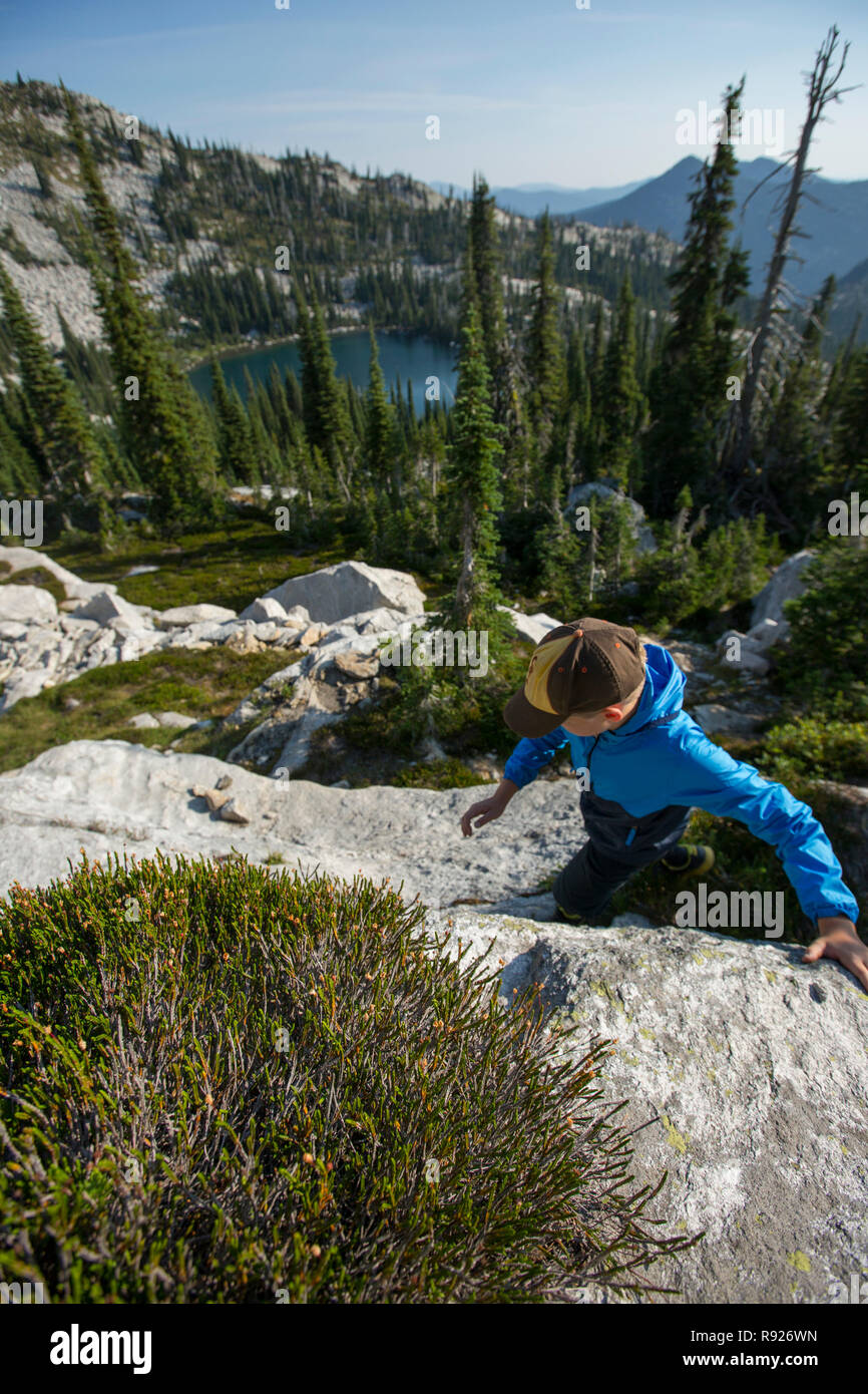 Photograph of a ten year old boy hiking in the mountains with a view of a lake in the background, Selkirk Mountains, Sandpoint, Idaho, USA Stock Photo