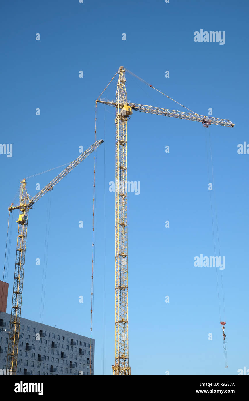 Big yellow construction tower crane on dwelling construction over blue