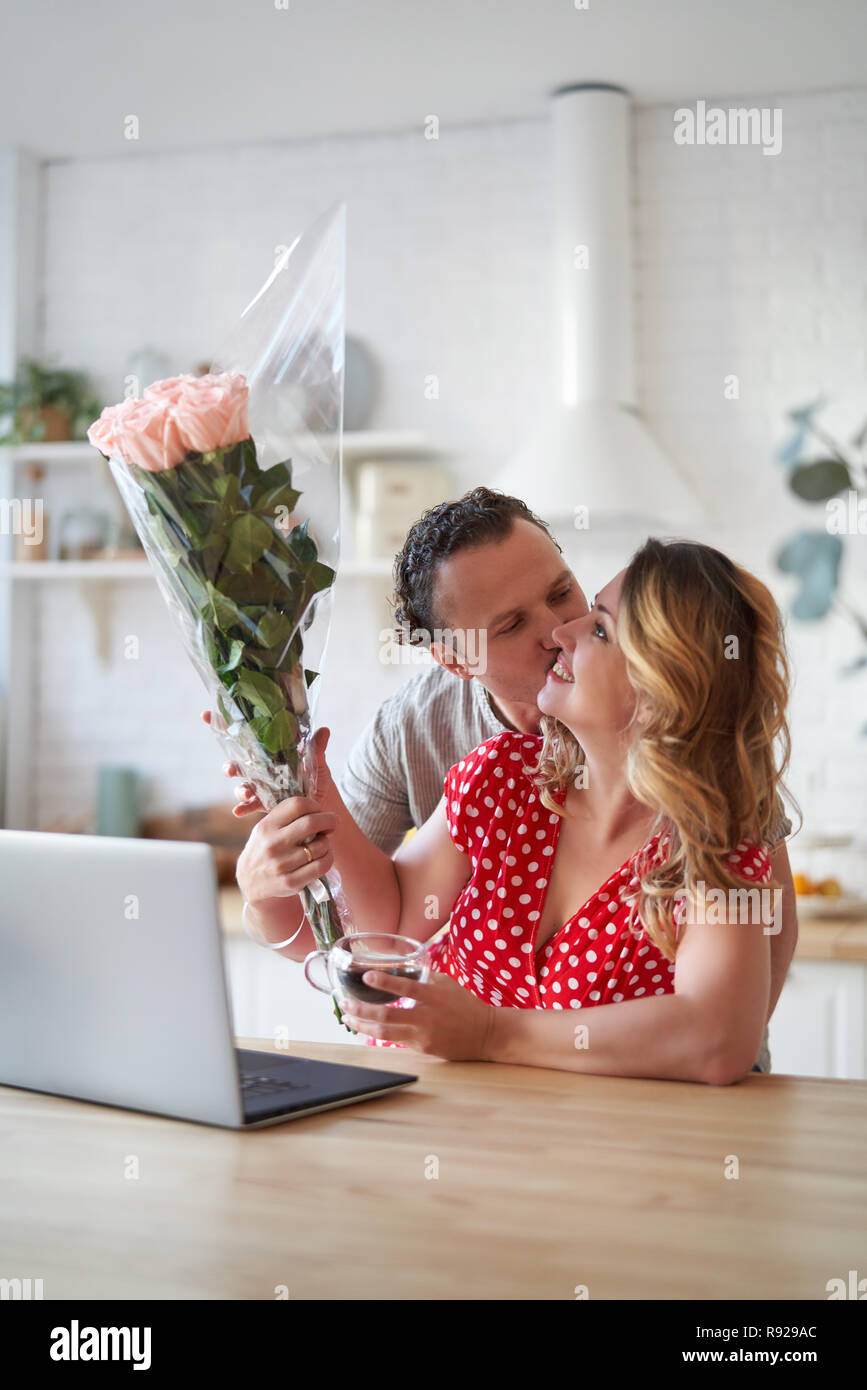 Summer holidays, love, relationship and dating concept - couple with bouquet of flowers in the kitchen. Stock Photo