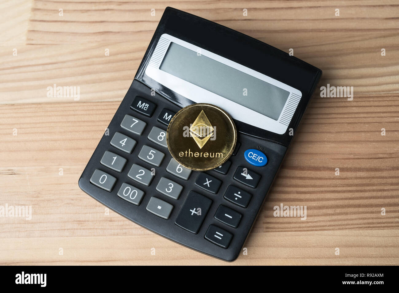 Golden physical Ethereum coin on calculator on wooden background.  Cryptocurrency market numbers abstract concept Stock Photo - Alamy