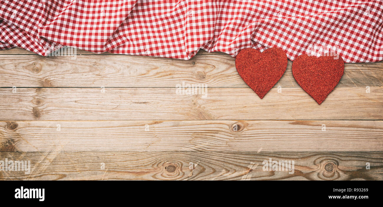 Valentines day. Top view of red fabric hearts and checkered white and red cloth against wooden background Stock Photo