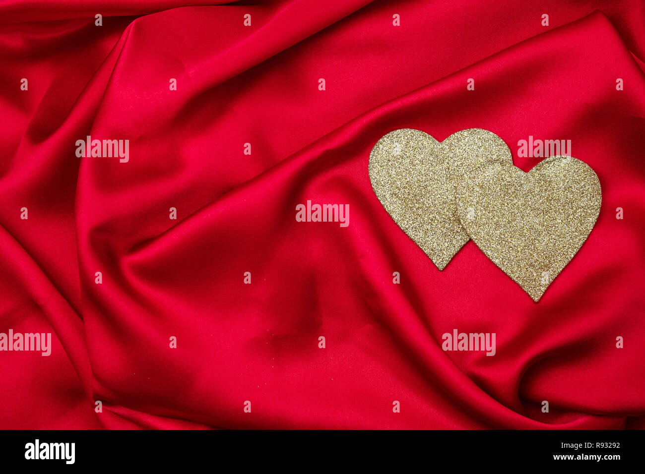 Valentines day. Top view of golden hearts on red silk background, wallpaper, copy space. Stock Photo