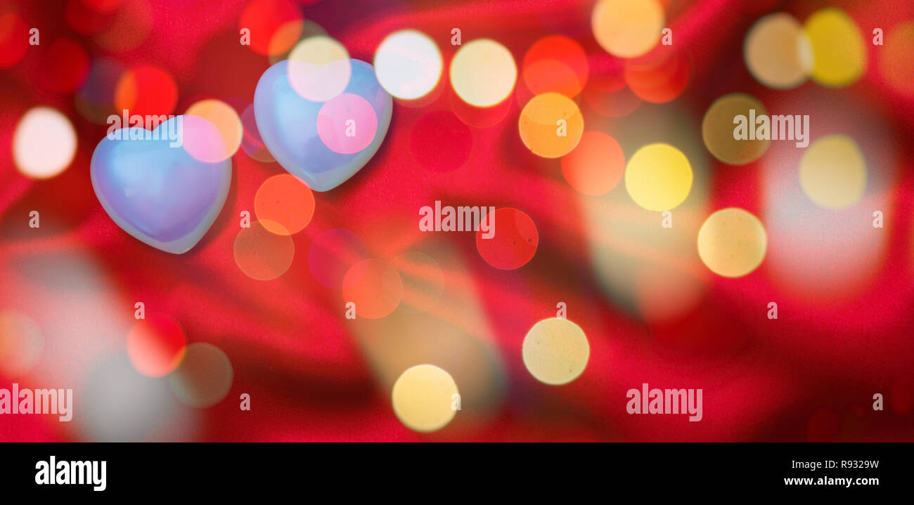 Valentines day. Top view of light blue glass hearts, bokeh and blurry on red silk abstract background, wallpaper. Stock Photo