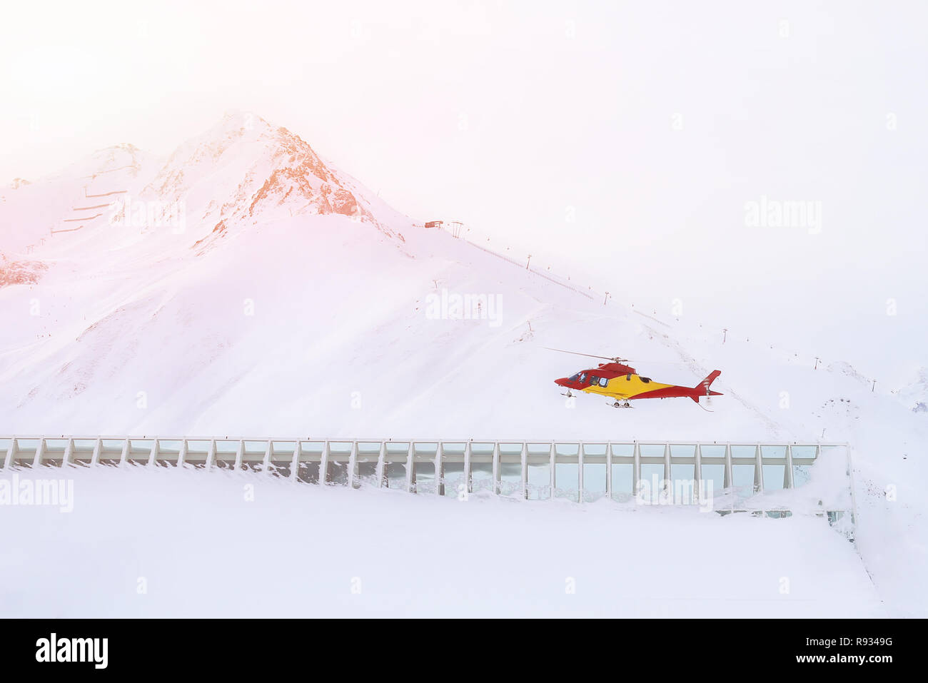 Rescue helicopter landing on slopes at ski resort in alpine mountains