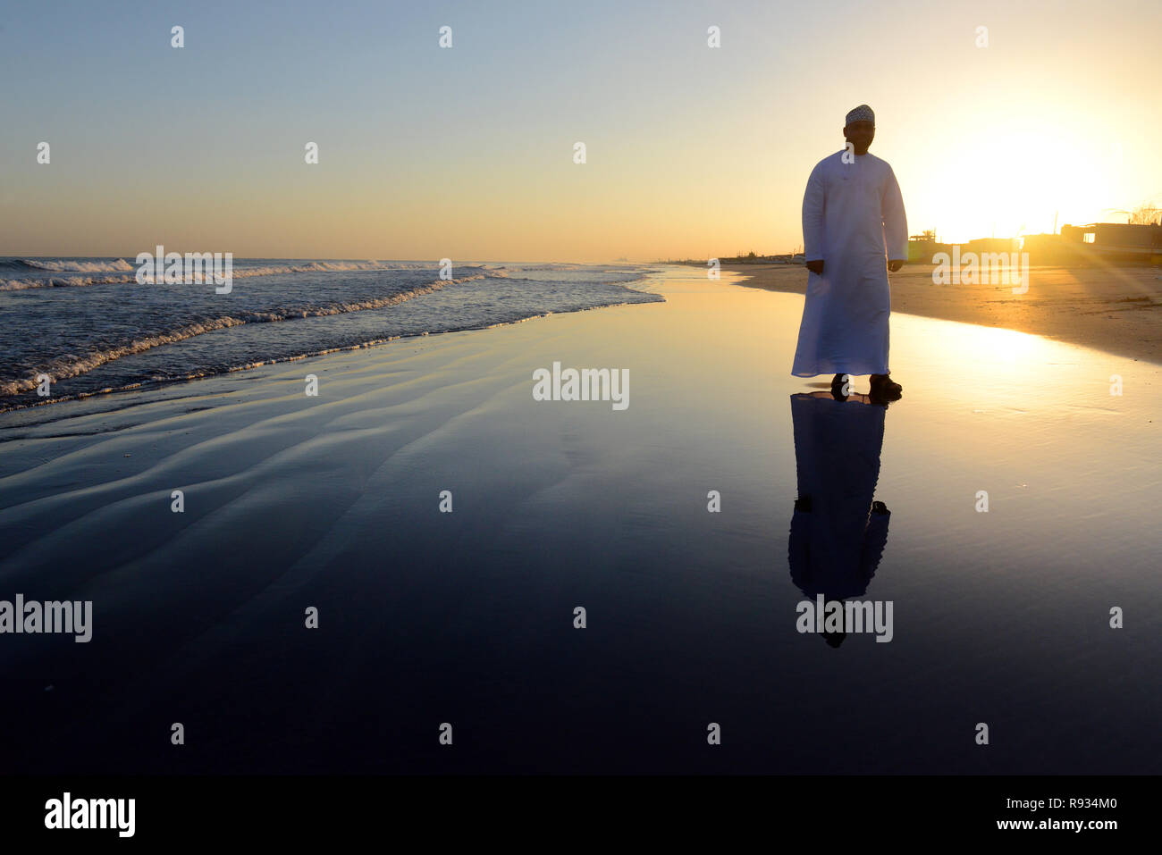 An Omani man walking on th Barka beach in Oman. Stock Photo