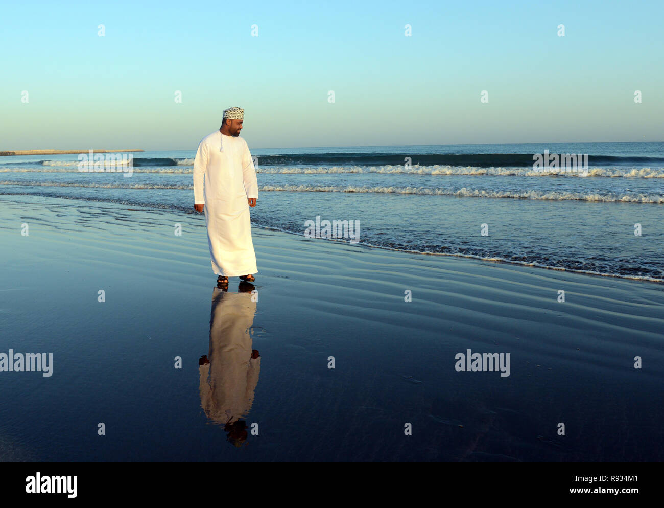 An Omani man walking on th Barka beach in Oman. Stock Photo