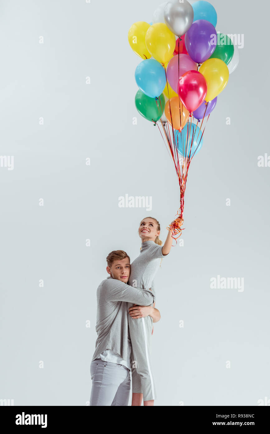 Hugging Balloons beautiful couple hugging while woman holding bundle of colorful ...