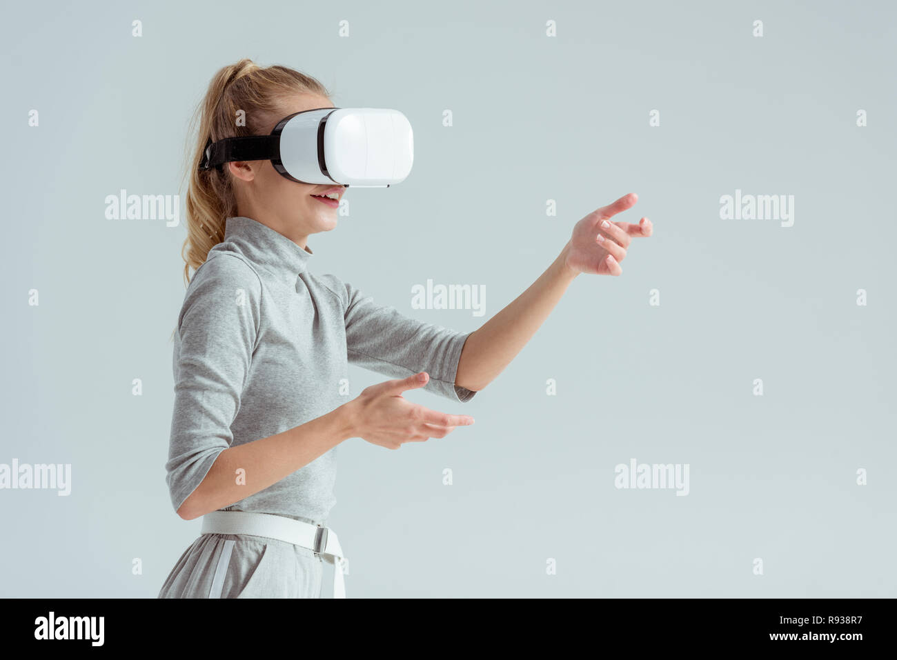 surprised woman gesturing while having virtual reality experience isolated on grey Stock Photo
