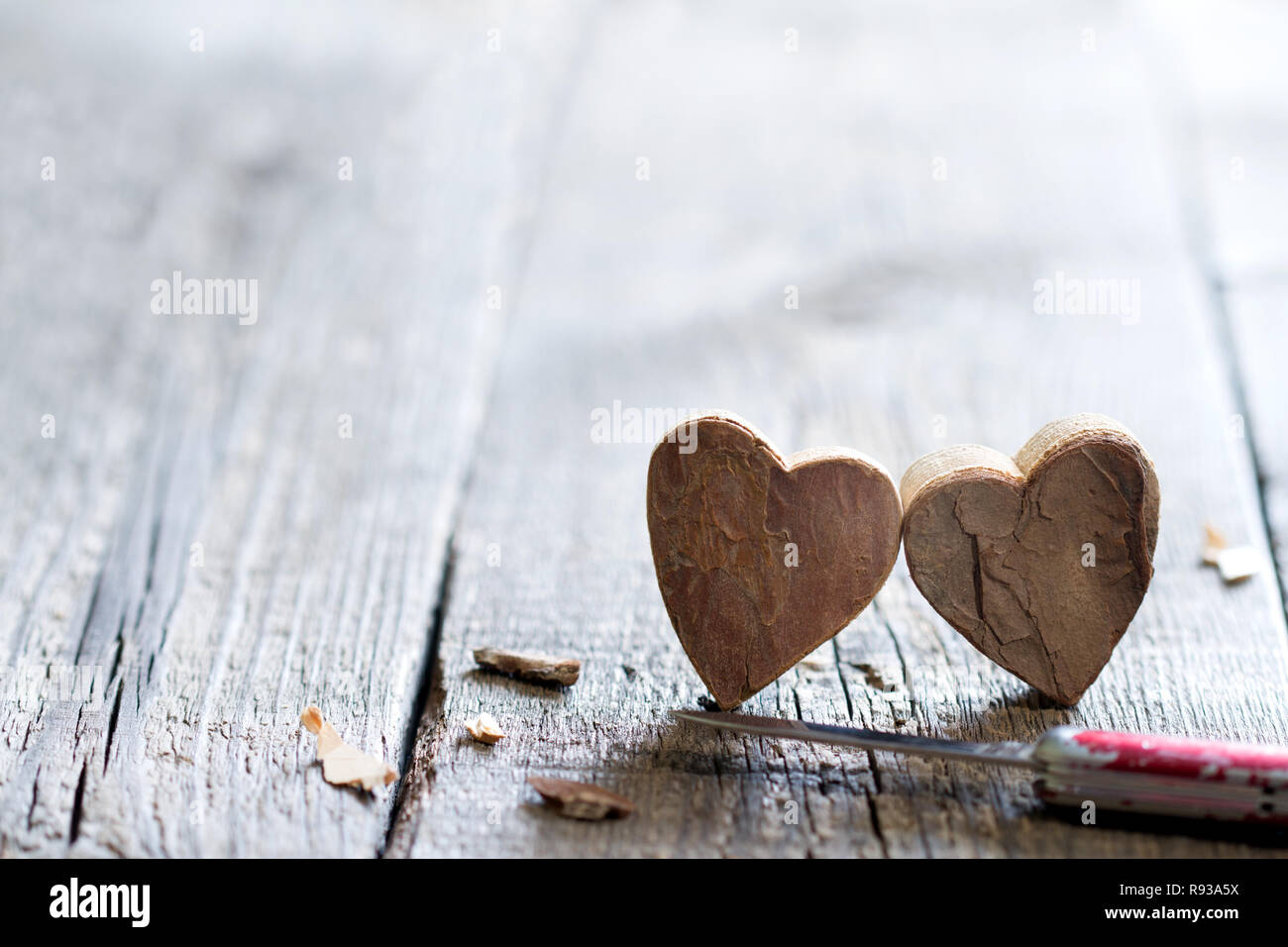 Couple carved wooden hearts and knife abstract love valentines background with free space Stock Photo