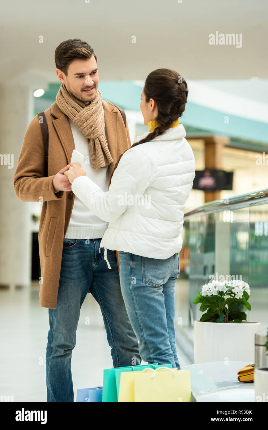 girl and smiling man in warm clothing holding hands and standing in ...