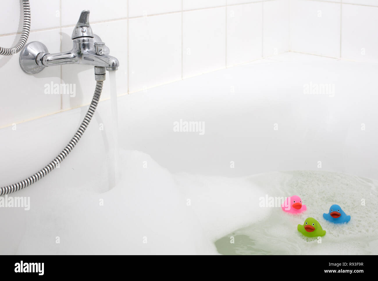 Pink, green and blue duck in a bathtub, surrounded by soap Stock Photo ...