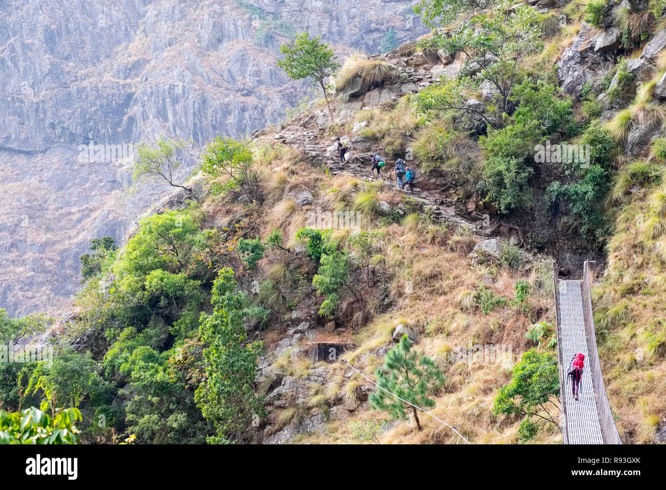 Trekkers crossing a suspension foot bridge on the Manaslu Circuit Trek, Nepal Himalayas Stock Photo