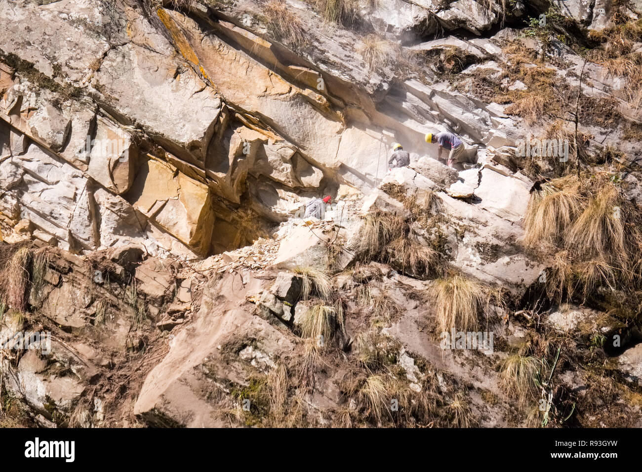 Construction workers making a new road into the mountains on a steep hillside in Nepal Stock Photo