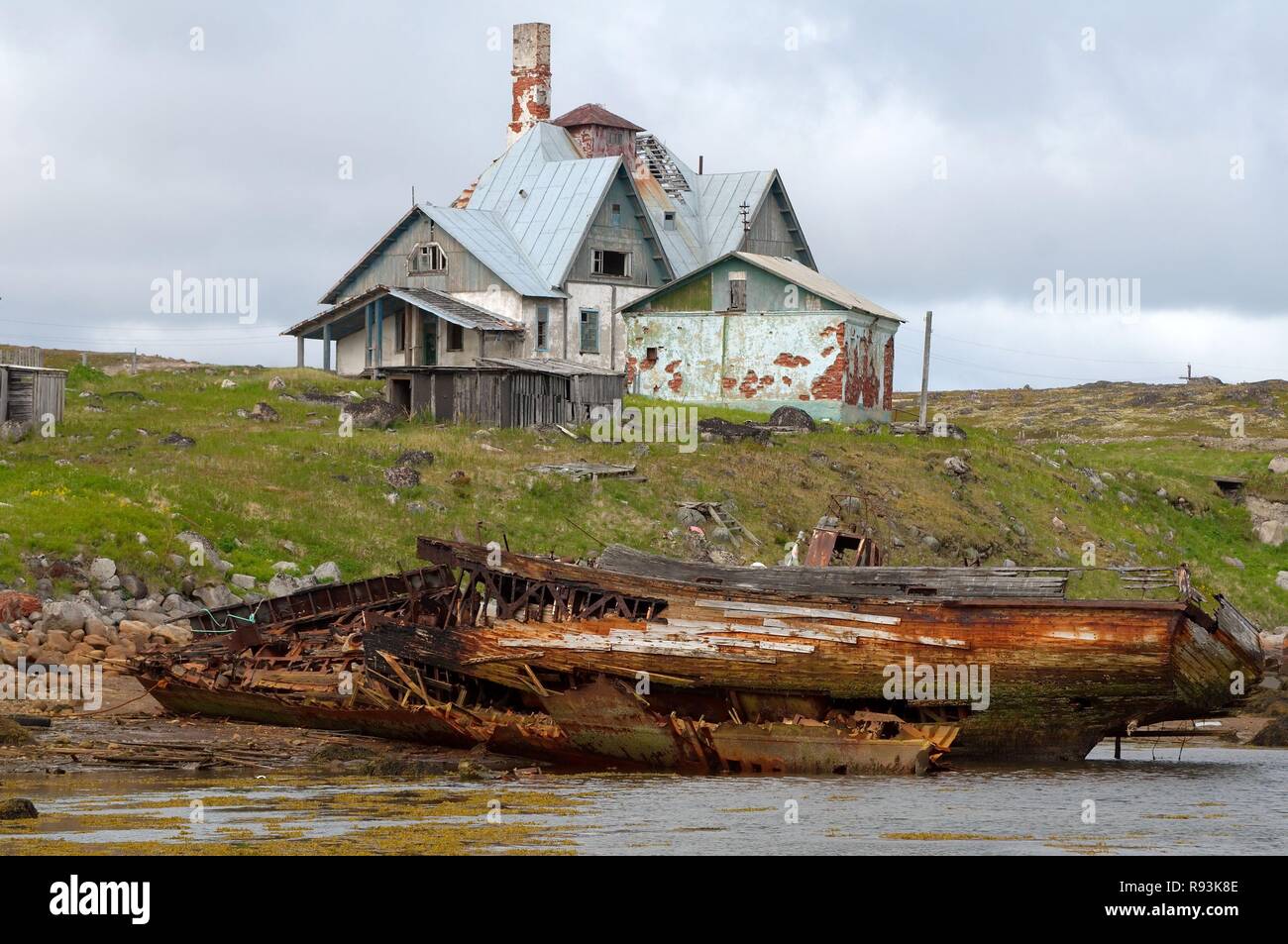 Derelict small fishing boat, MRB, in front of a derelict house in a rural locality on the Barents Sea, Dalniye Zelentsy Stock Photo