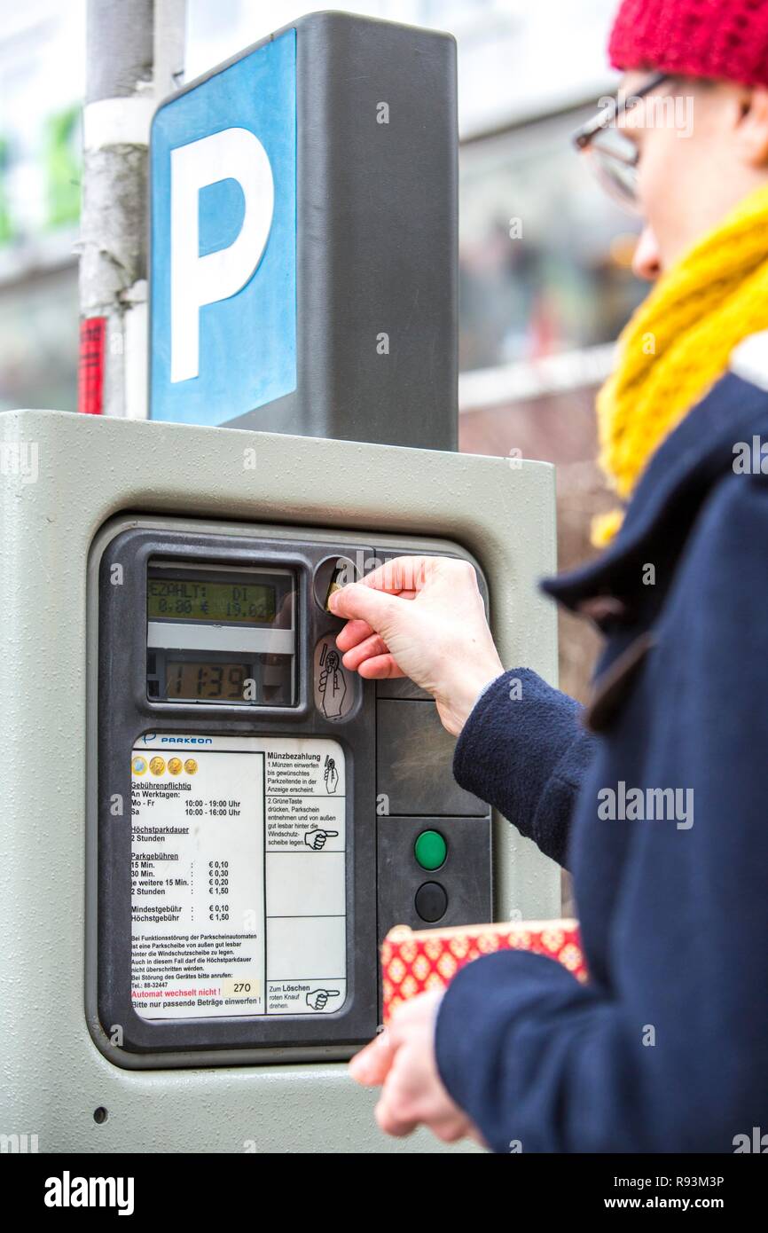 Woman purchasing a parking ticket from a parking ticket vending machine ...