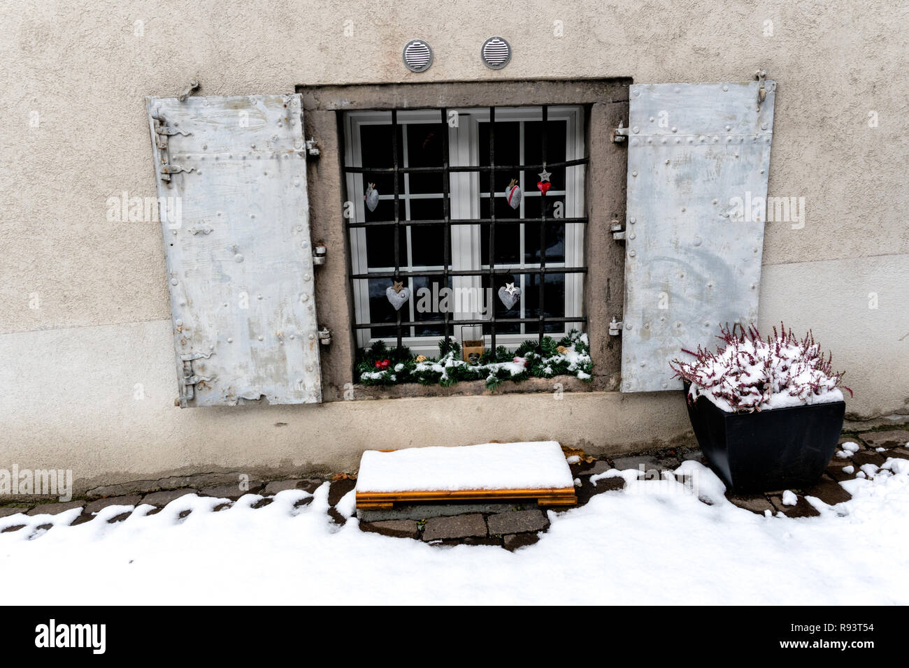 imaginative advent calendar and Christmas decorations hanging from a ground floor window in a snowy village in the Swiss Alps during the holidays Stock Photo