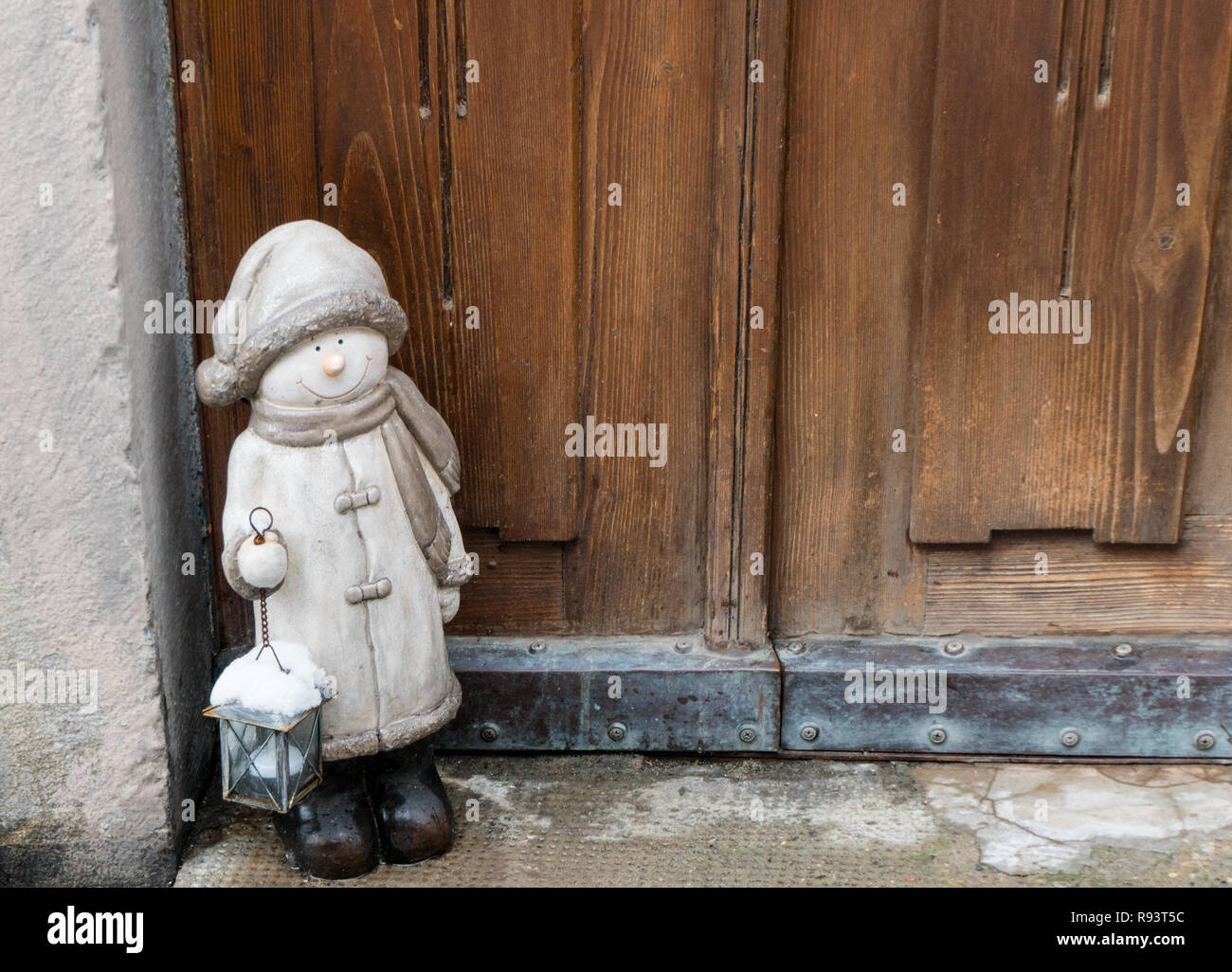 close up of a wooden door and entry with an inviting and decorative Christmas statue in the corner Stock Photo