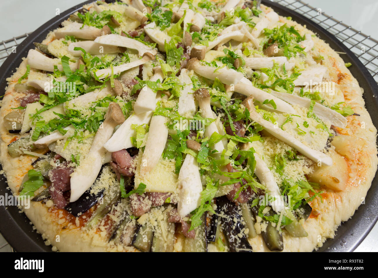 Fresh homemade pizza ready to bake, with King Trumpet mushroom (Pleurotus eryngii), aka French Horn, King Oyster, King Brown mushroom; celery, bacon Stock Photo
