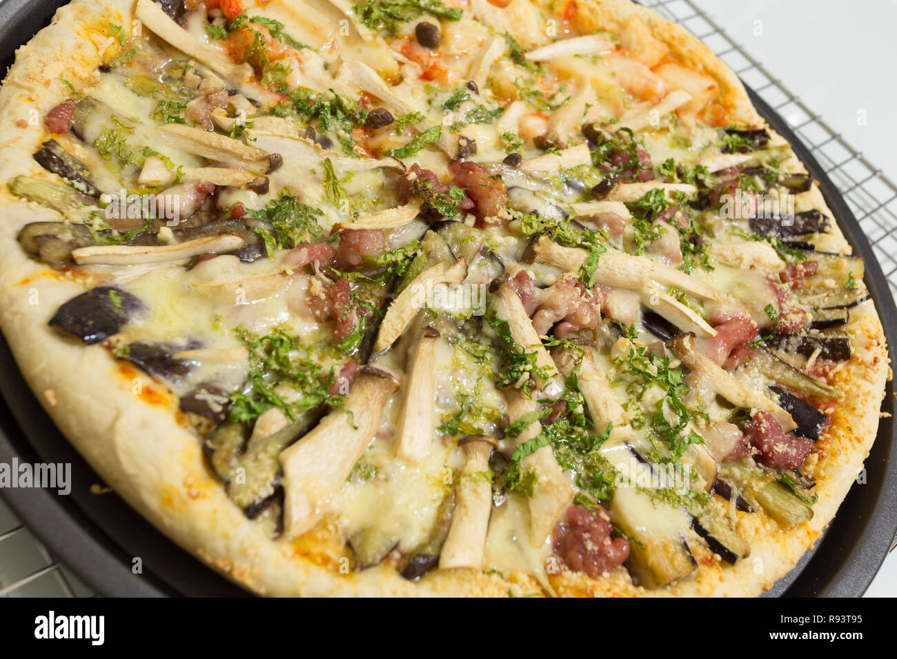 Fresh homemade pizza ready to eat, with King Trumpet mushroom (Pleurotus eryngii), a.k.a. French Horn, King Oyster, King Brown mushroom; celery, bacon Stock Photo