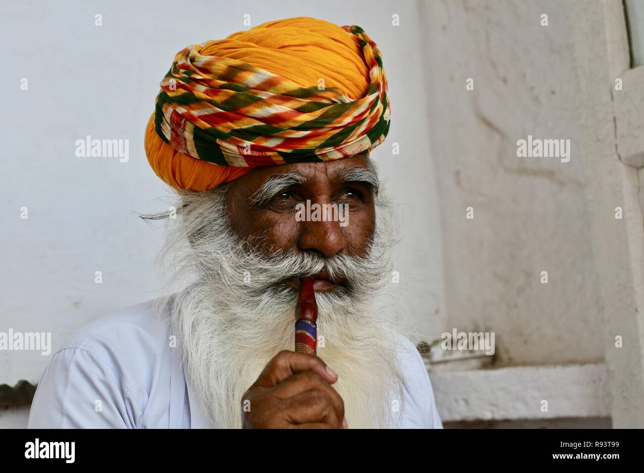 An Indian man in white with orange and yellow turban Stock Photo