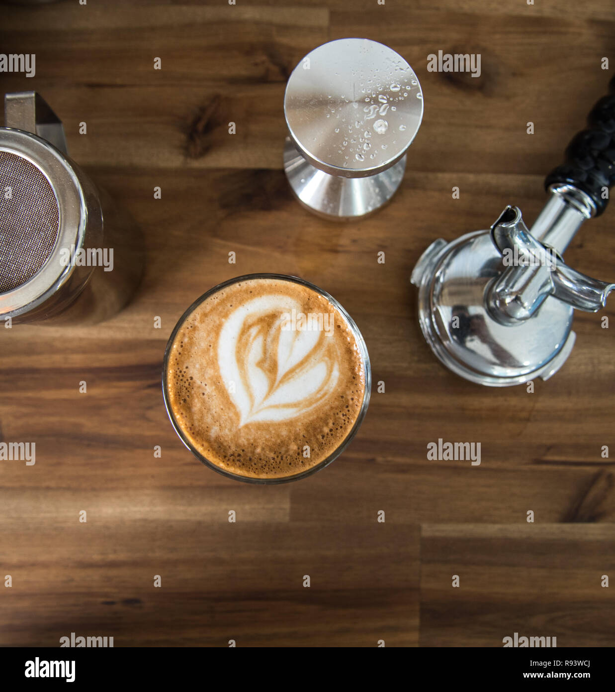Coffee latte art on a bench with coffee machine tools around it. Cafe latte with a heart on it, beautiful warm drink Stock Photo