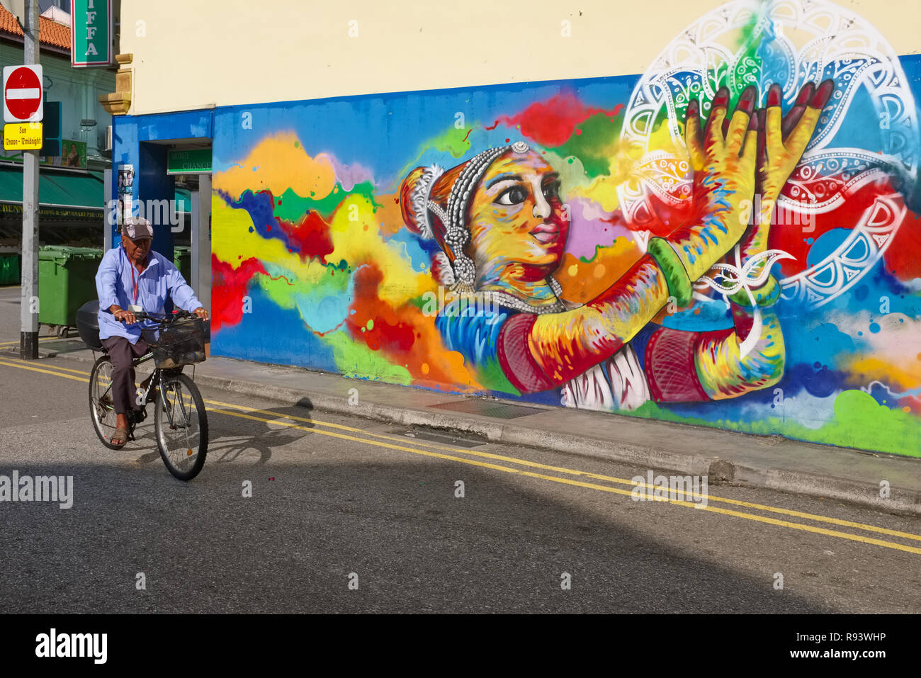 A cyclist passing a wall painting depicting a classical Indian dancer, in Clive Street, Little India, Singapore Stock Photo