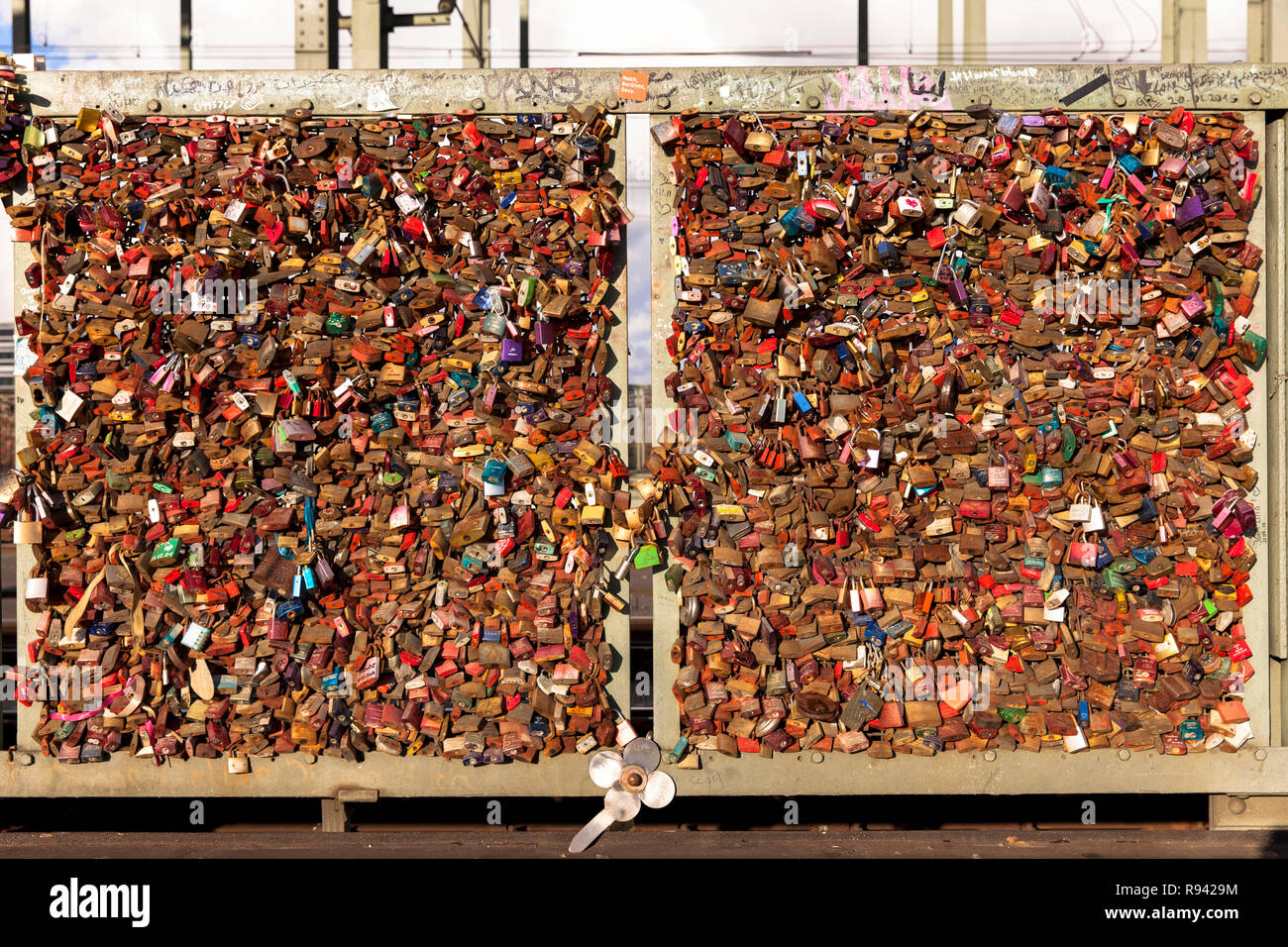 Germany, Cologne, padlocks on fence of footpath of the Hohenzollern railway bridge. Young couples seal their love with engraved padlocks and throw the Stock Photo