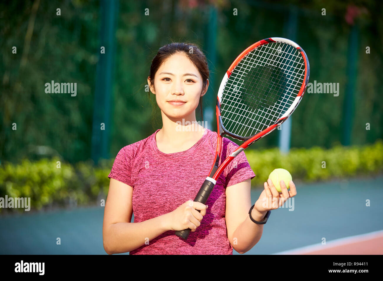 outdoor portrait of a young asian tennis player looking at camera smiling Stock Photo
