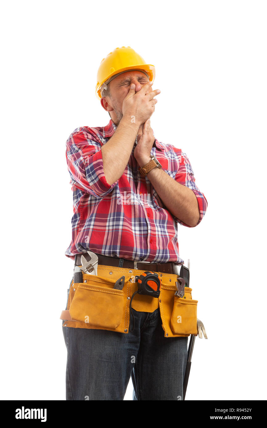 Tired builder covering mouth with hand as yawning isolated on white studio background Stock Photo