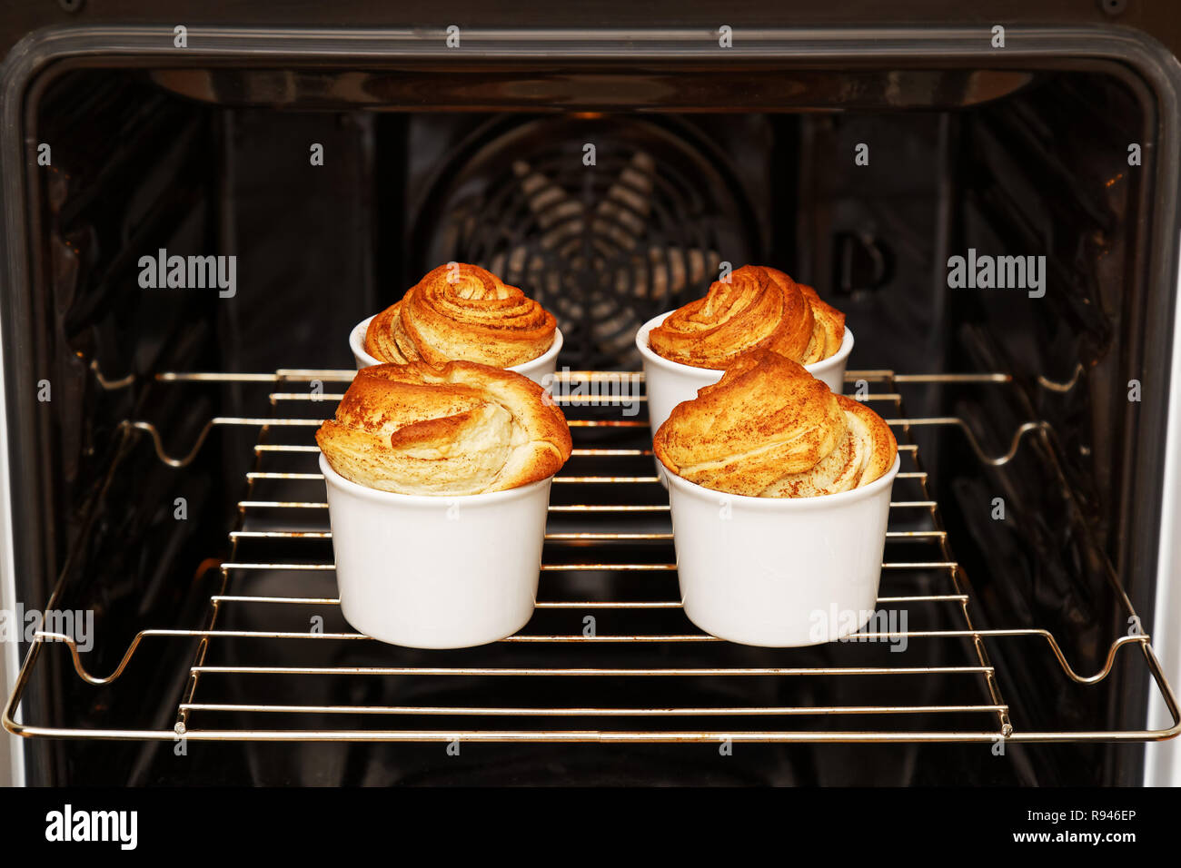 https://c8.alamy.com/comp/R946EP/homemade-cinnamon-rolls-from-yeast-dough-in-white-ceramic-mold-is-baked-in-the-oven-R946EP.jpg