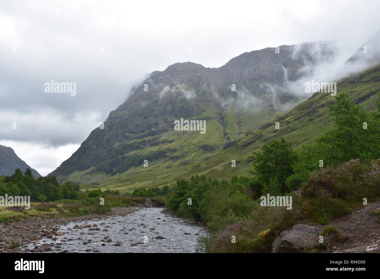 The River Coe Flowing Through The Valley of The Glencoe Mountain Range in The Scottish Highlands. Taken on a Raining and Overcast August Day. Stock Photo