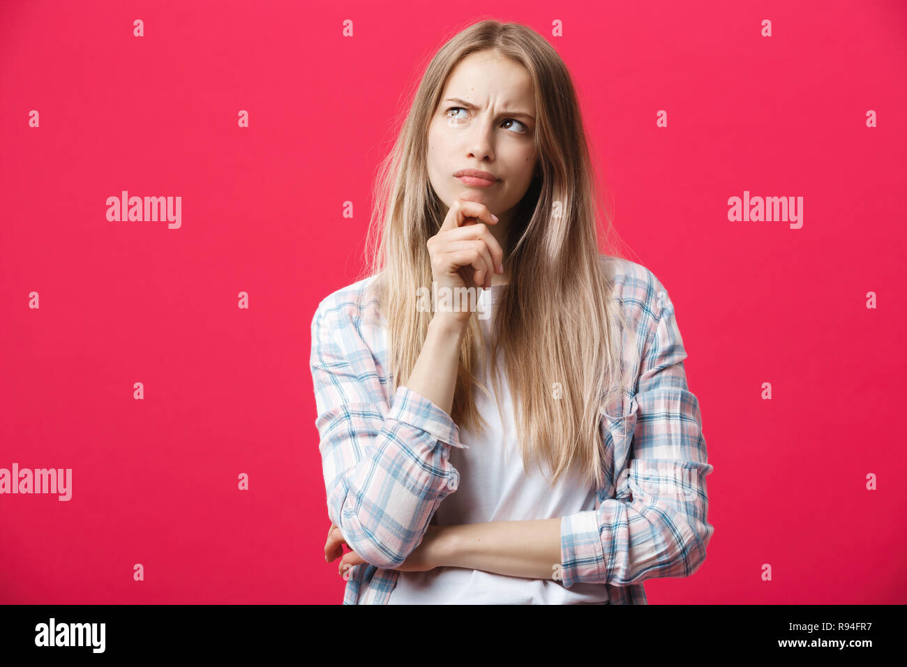 Studio portrait of beautiful young woman thinking and looking upwards ...