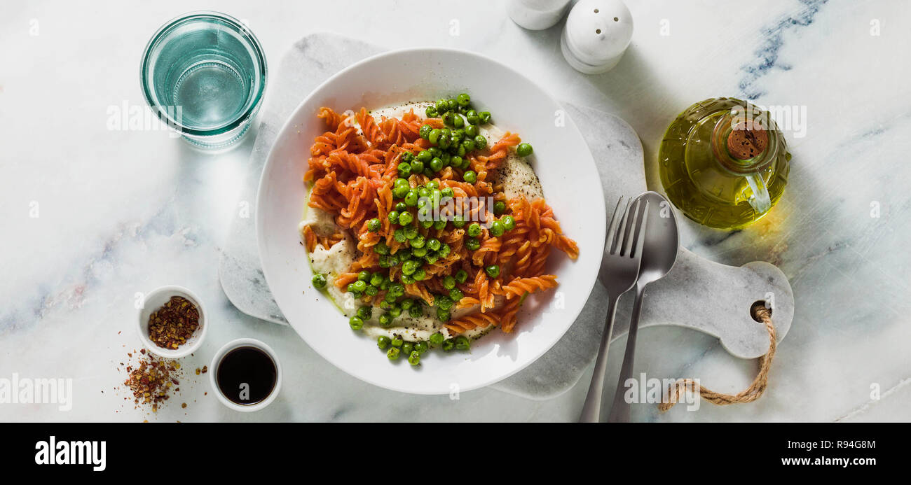 banner of gluten-free healthy vegan red lentil pasta with green peas and cauliflower puree with garlic. tasty mac and cheese fusilli  for celiac disea Stock Photo