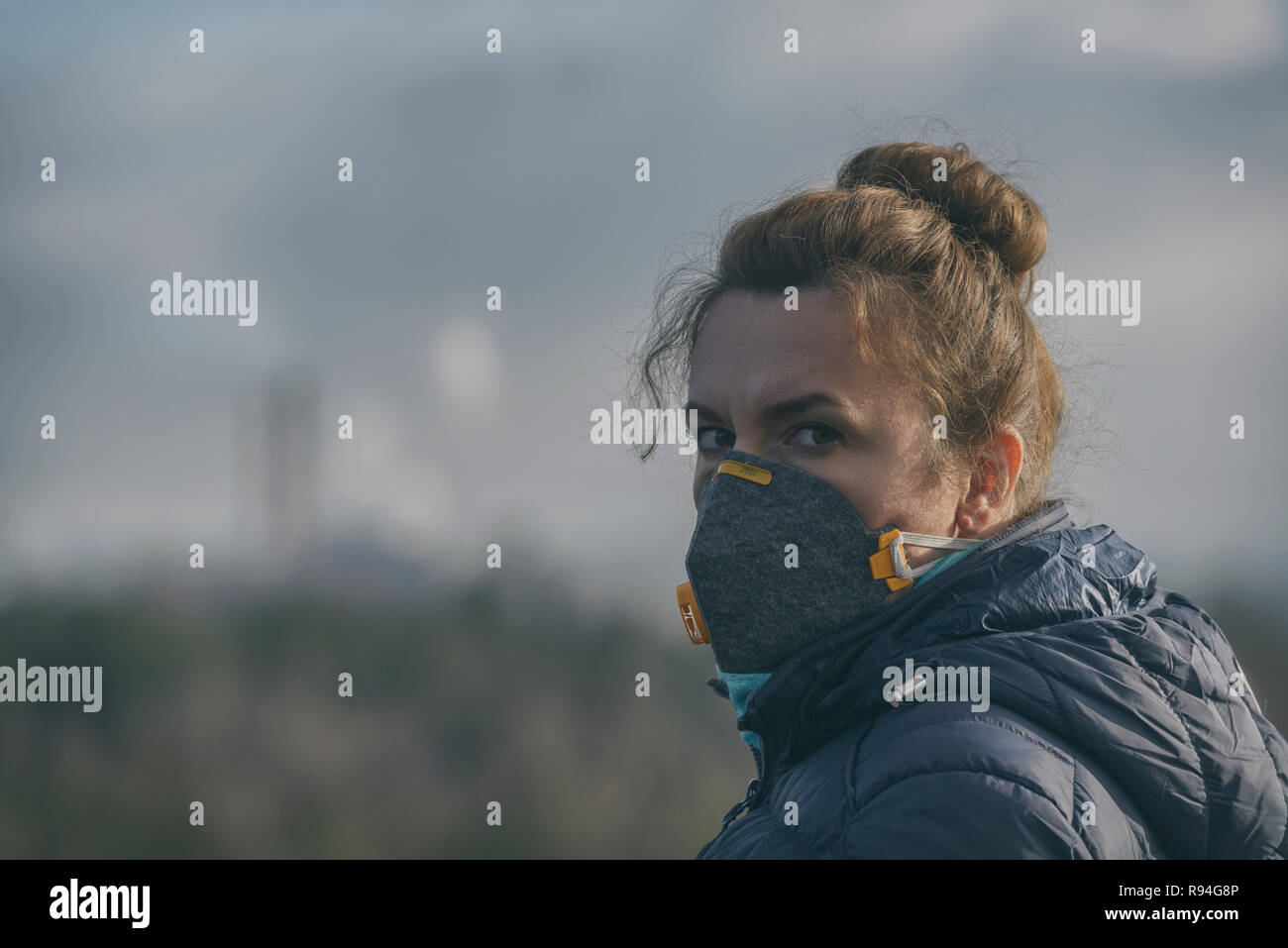 Woman wearing a real anti-pollution, anti-smog and viruses face mask; dense smog in air. Stock Photo