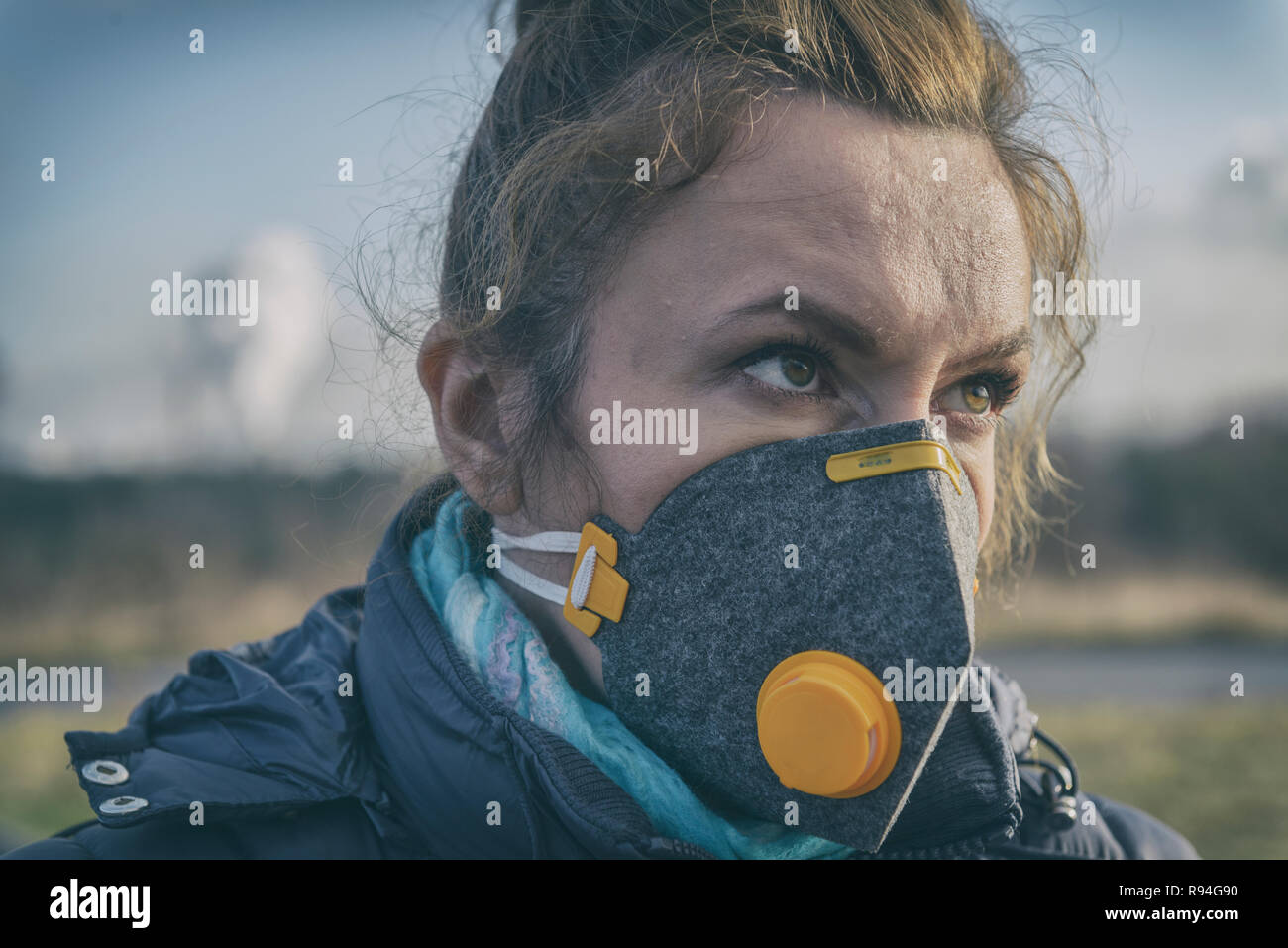 Woman wearing a real anti-pollution, anti-smog and viruses face mask; dense smog in air. Stock Photo