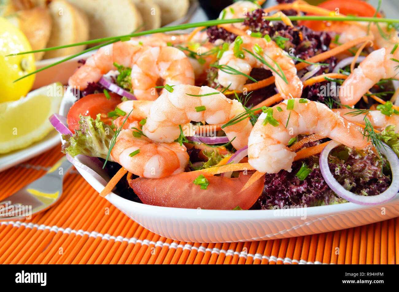 Delicious salad with lollo rosso and prawns, in the background lemon and dill Stock Photo