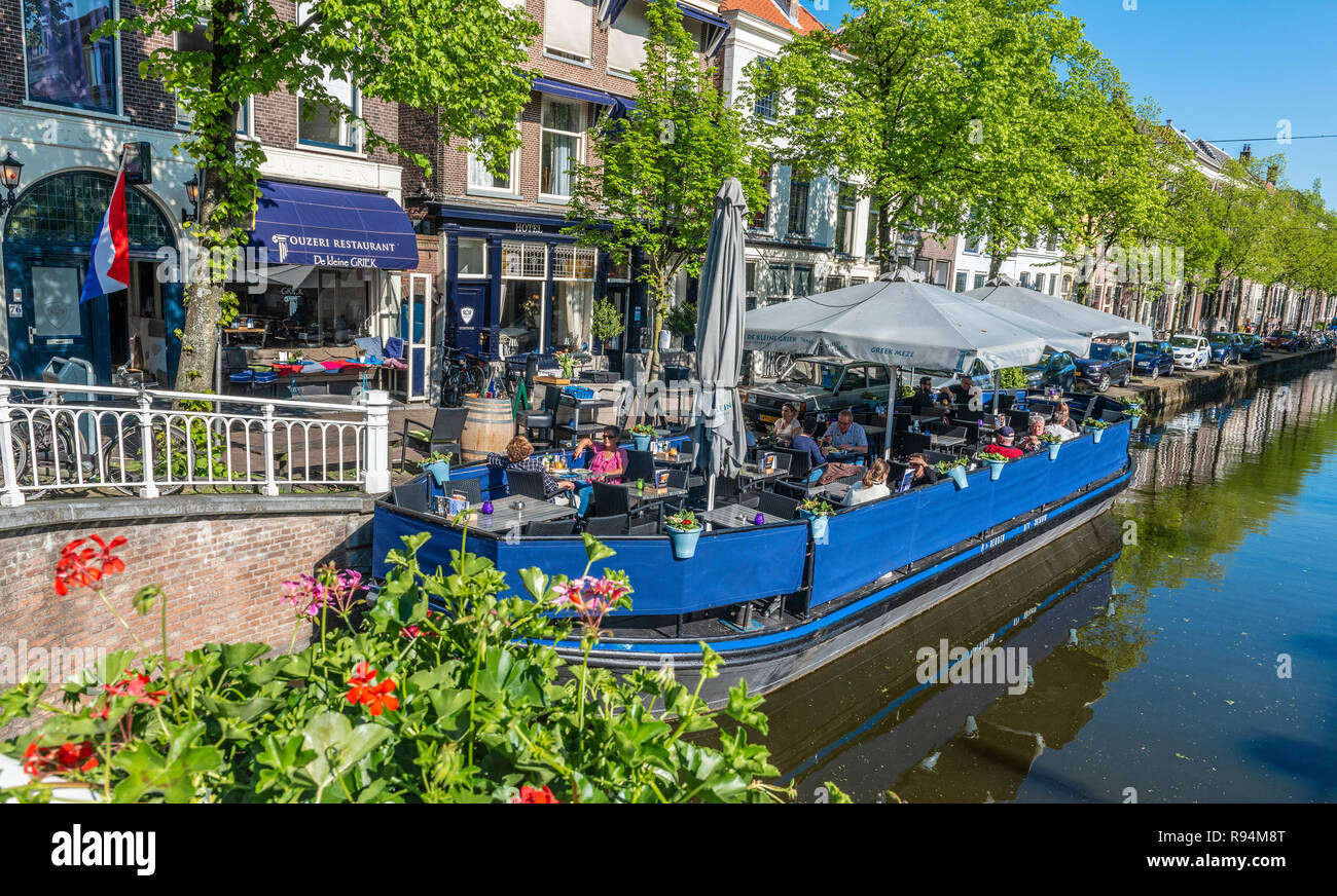 Barge moored at the side of a canal and used as a floating restaurant on a sunny pring day in the centre of  the town of Delft,Holland,The Netherlands Stock Photo