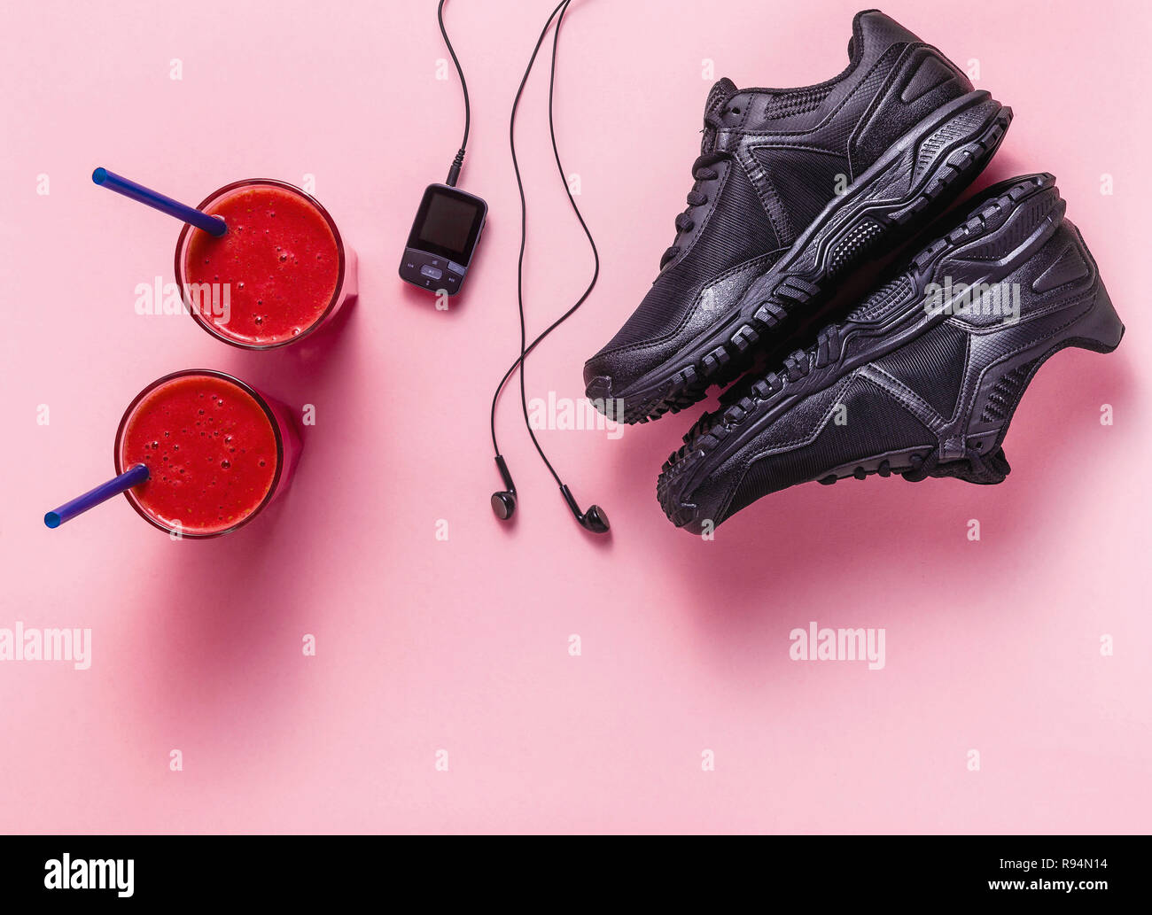 red fresh fruit smoothies, mp3 player with headphones and black sneakers on  a pink background. concept of youth, music, sport and health Stock Photo -  Alamy
