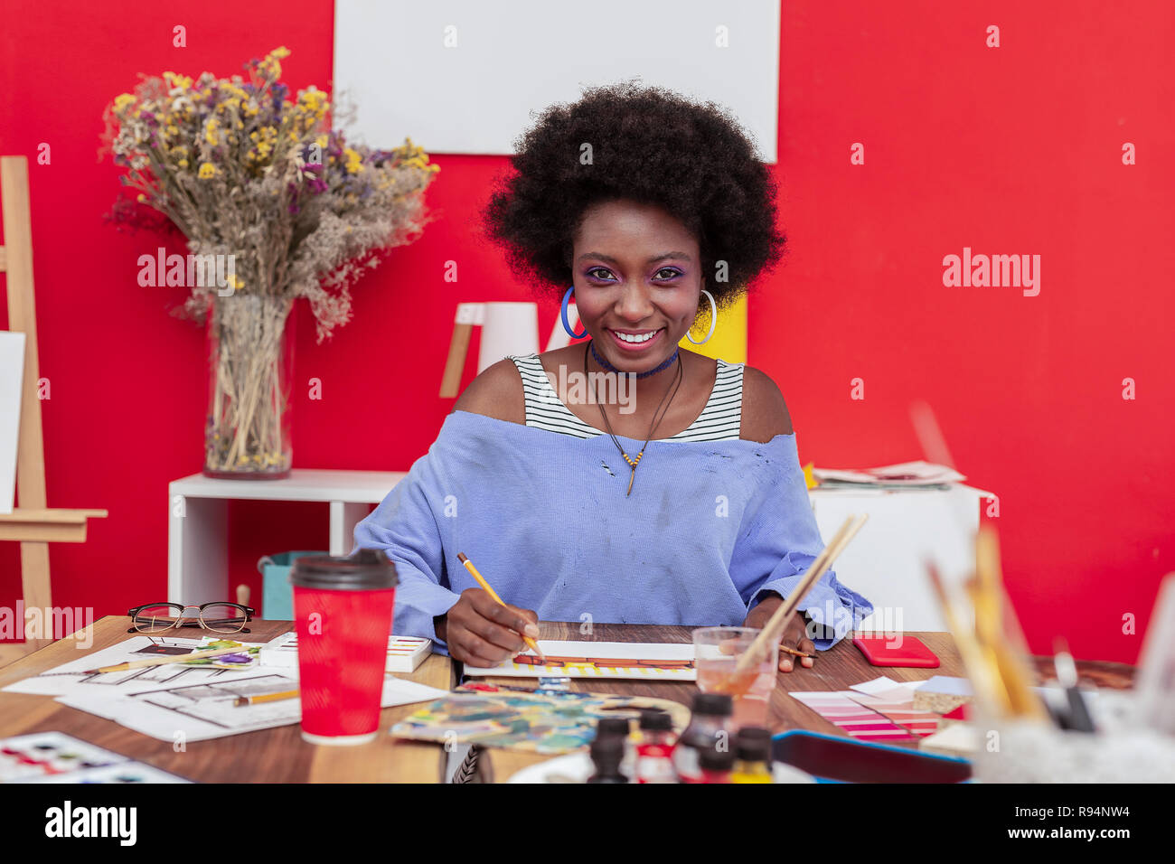 Cheerful designer wearing massive earrings smiling broadly Stock Photo