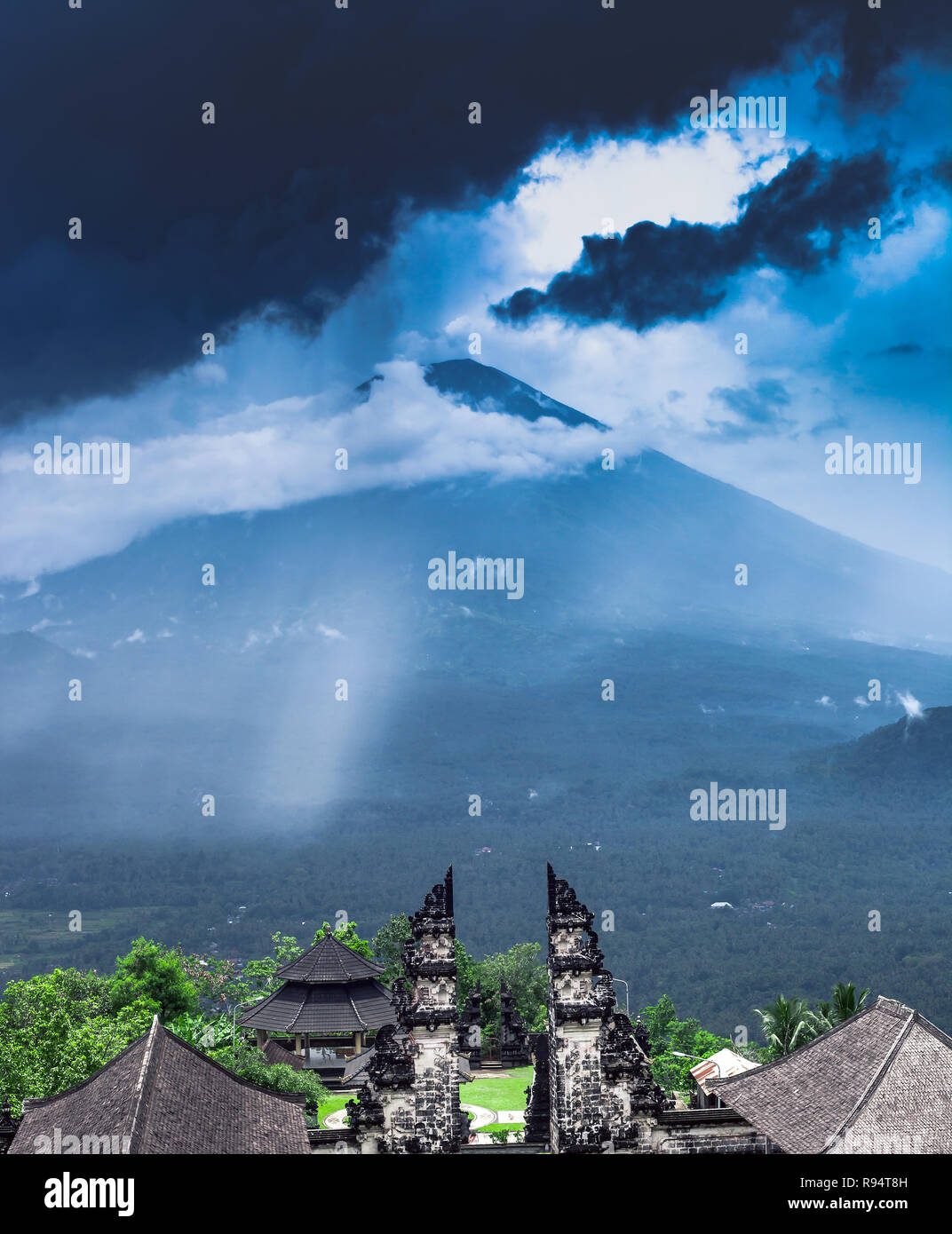 Summer landscape with Pura Penataran Agung Lempuyang temple. Candi bentar and view to Agung mount in thunderstorm dark clouds before tropical rain Stock Photo