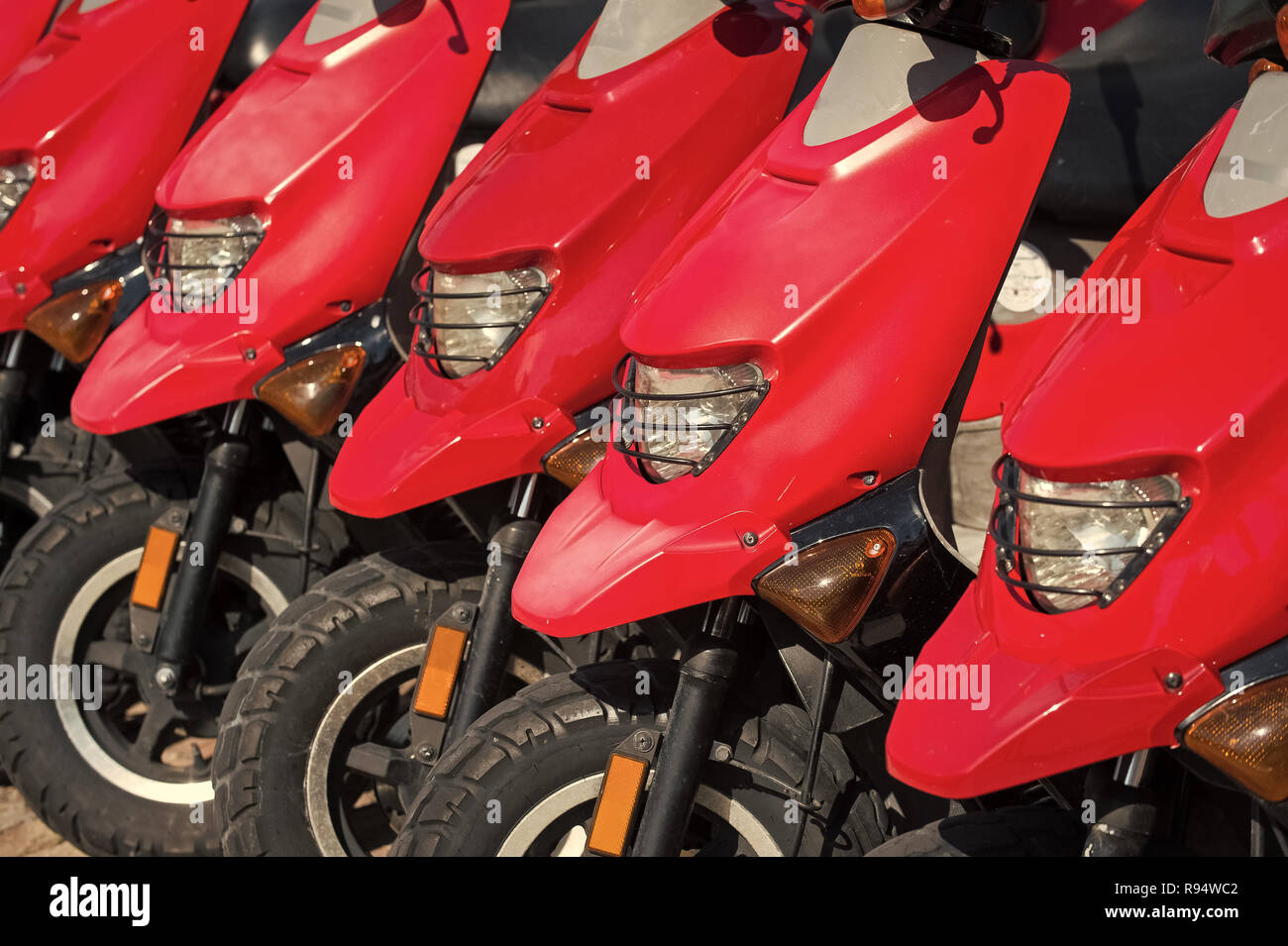 red scooters or motorcycles for sale or hire standing in row with
