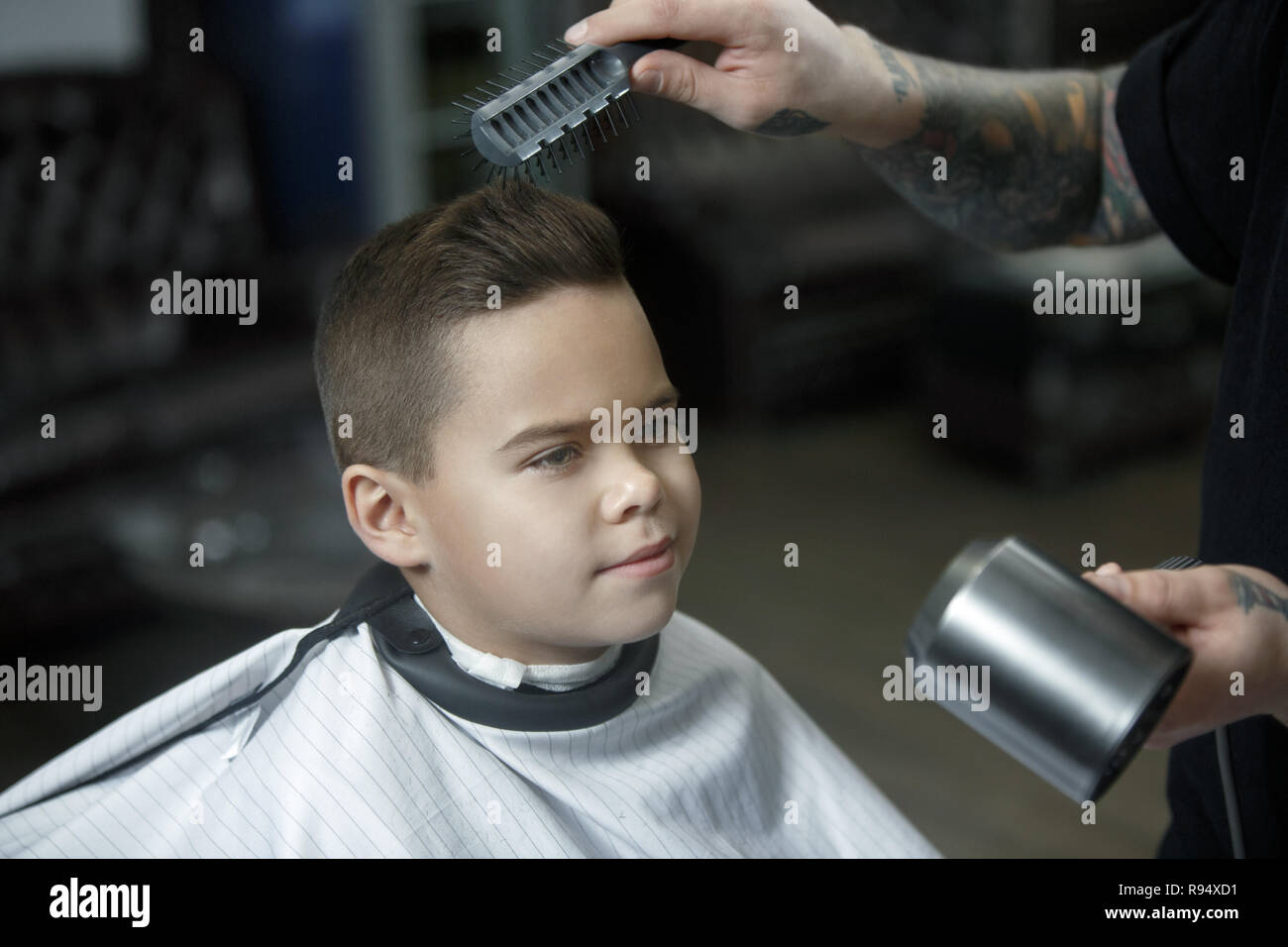 Children Hairdresser Cutting Little Boy Against A Dark Background