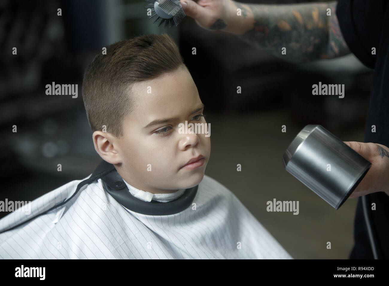 Children Hairdresser Cutting Little Boy Against A Dark Background