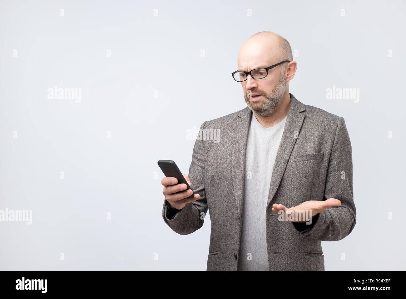 Puzzled bald man reading sms with emotional face expression Stock Photo