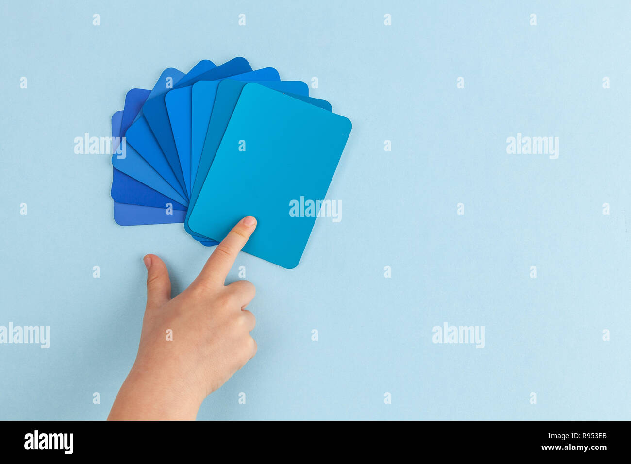 Child's hand pointing at color samples cards - hues of blue with copy space Stock Photo