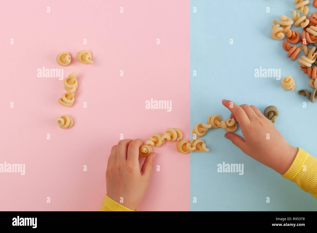 Child's hands making an arrangement from pasta shells with copy space Stock Photo
